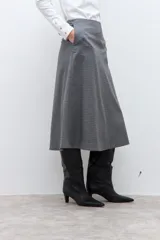 Falda midi de corte acampanado con estampado de cuadros pequeños en tonos grises. Presenta un diseño de tiro alto y estructura firme.