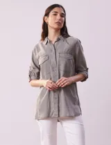 Camisa color gris de tencel, marca Hester & Orchand. Cuello con solapa y abertura central con botones ocultos. Delantera con bolsillos. Largo de manga regulable con presilla y botón.