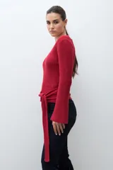 Sweater de punto acanalado color rojo, con escote en V, mangas largas acampanadas y lazo ajustable en la cintura.
