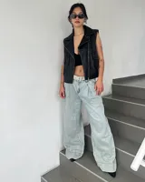 Pantalón de jean de corte wide leg en color celeste claro, con diseño de pinzas en la cintura y cinturón integrado con hebilla metálica.