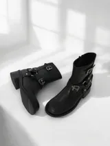 Bota corta de cuero negro con hebillas metálicas y cierre interno.