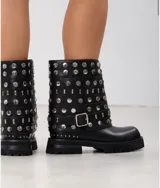 Botas de caña media color negro, con suela track y diseño cargado de tachas metálicas plateadas circulares y rectangulares. Incluye una tira ajustable con hebilla metálica en la zona del tobillo.