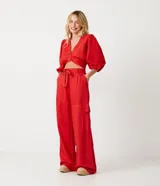 Pantalón acampanado de viscosa color rojo, con trabillas en la cintura, lazo y bolsillos cargo laterales.