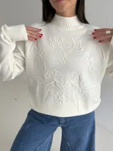 Sweater de punto color blanco con cuello polera, manga larga y diseño bordado al tono con motivos florales en el frente y las mangas.