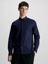 Camisa azul marino de popelín de algodón elástico, corte slim, con cierre frontal de botones y logo bordado en el pecho.