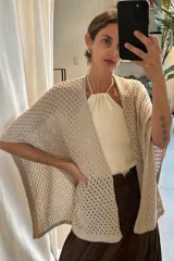 Ruana de tejido artesanal en color crudo, con diseño de calados geométricos y terminación de borde recto.