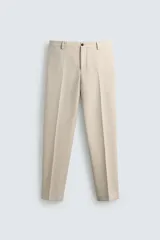 Pantalón de corte recto confeccionado en tejido con lana, color beige. Presenta bolsillos frontales, bolsillos traseros de vivo y cierre frontal con cremallera y botón.