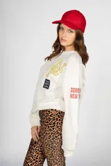 Sweater blanco de algodón con cuello redondo, mangas largas y puños acanalados. Estampado frontal con letras "NYC" y la frase "The City Life".