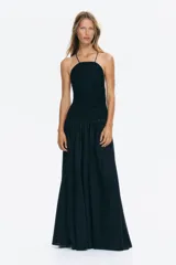 Vestido largo color negro con cuerpo de crochet en la parte superior, escote halter con tirantes finos y falda fluida con leve vuelo confeccionada en mezcla de lyocell. Presenta diseño de espalda descubierta.