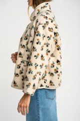 Campera de corderito con estampado floral, cuello alto y cierre frontal con botones a presión. Posee puños elásticos y un diseño de ajuste al cuerpo.