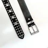 Cinto negro de cuero sintético con hebilla metálica plateada y tachas plateadas de diferentes tamaños.