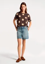 Blusa de manga corta con cuello redondo, confeccionada en tejido ligero con estampado de rayas verticales en tonos azul marino y celeste sobre fondo blanco.