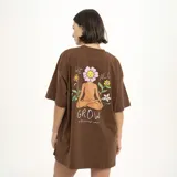 Remera marrón con estampado pequeño en el pecho que dice "We all grow" con una flor.