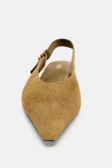 Zapato plano destalonado de punta fina, color verde oliva/mostaza, confeccionado en piel con acabado de gamuza. Posee una tira ajustable con hebilla metálica dorada en el talón.