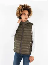 Chaleco acolchado verde militar de nylon con cuello alto y cierre frontal con cremallera. Tiene dos bolsillos laterales con cremallera, logo de Tommy Hilfiger bordado en el pecho y detalles distintivos de la marca.