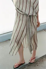 Vestido midi de Zara Woman Collection, con estampado de rayas verticales y detalles ornamentales, escote en V, mangas cortas con aberturas en los hombros, y fajín integrado con lazo lateral del mismo tejido.