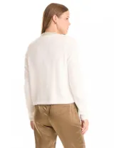 Chaqueta corta de tejido tipo mohair en color blanco, con cuello a la base decorado con bordado de perlas y canutillos. Presenta bolsillos simulados en el frente con apliques de brillos y cierre mediante broche interno.