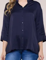 Camisa de satén azul marino con cuello mao, escote en V y mangas tres cuartos con hombro caído. Presenta silueta holgada, cierre frontal con botones y ruedo asimétrico.