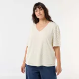 Camiseta de encaje color beige con diseño calado, escote en V y mangas cortas abullonadas.