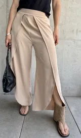 Pantalón color beige de corte palazzo con abertura lateral en la parte inferior de la pierna.