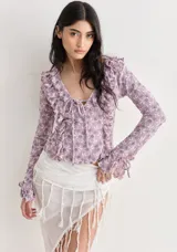 Top blanco de encaje con escote en V, volados y mangas largas con lazos.