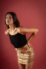 Minifalda dorada de cuerina con cierre, botón y bolsillos delanteros.