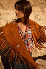 Chall de gamuza natural con diseño de flecos largos en todo el borde y detalle de pins metálicos decorativos en la parte frontal.