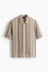 Camisa de punto pointelle con estilo crochet y rayas verticales en tonos marrones y beige. Presenta mangas cortas, cuello inglés, cierre frontal de botones y corte estándar.