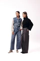 Campera de jean negra con mangas largas tejidas en crochet con diseño calado y detalles florales en relieve. Presenta cuello camisero, cierre frontal y bolsillos en el pecho.