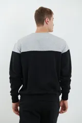 Sweater deportivo de hombre con escote redondo, diseño colorblock con la parte superior en gris claro y el cuerpo y mangas en negro. Presenta puños y cintura elastizados.
