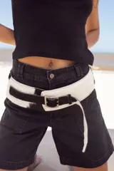 Cinto faja de cuero con estampado de vaca en blanco y negro, con hebilla metálica rectangular.