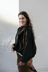 Campera bomber de tela gamuzada negra, con diseño oversize, mangas amplias tipo murciélago y cierre frontal metálico.