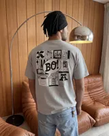Remera gris de corte regular con estampa gráfica en la espalda que presenta un collage de estilo cómic con la palabra 'BO!' en el centro.