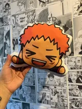 Peluche con forma de personaje de anime con pelo naranja y expresión sonriente.