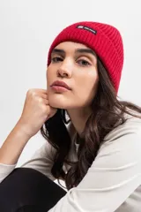 Gorro de lana tejido color lila con etiqueta negra con logo en el frente.