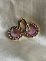 Aros de acero quirúrgico con dije circular de resina rosa y borde de strass dorados.