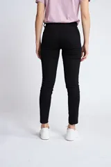 Pantalón de gabardina corte skinny, color beige, con diseño de cinco bolsillos, cierre de cremallera y botón frontal.