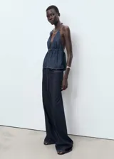 Pantalón de jean estilo wide leg, de tiro bajo y corte largo, con diseño de cinco bolsillos, trabillas para cinturón y cierre frontal con botón y cremallera.