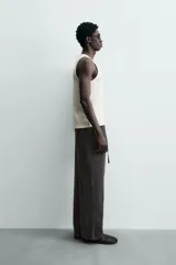 Pantalón de corte regular fit confeccionado en mezcla de algodón y lino. Presenta cintura elástica con cordón ajustable, cierre frontal con cremallera y botón, bolsillos laterales y bolsillo trasero de vivo con botón.