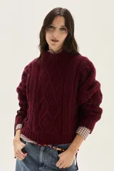 Polera de tejido de punto con diseño de ochos y detalles de tientos laterales en contratono, cuello alto acanalado y mangas largas.