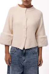 Chaqueta tejida de silueta recta con botones frontales y mangas tres cuartos terminadas en puños de piel sintética suave. Diseño versátil que permite usarla con los botones hacia adelante o hacia atrás.