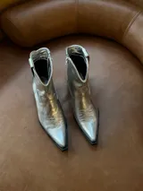 Bota texana de caña corta color plateado, con cierre lateral y bordados decorativos.