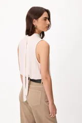 Blusa sin mangas color crema, con cuello alto fruncido y diseño holgado.