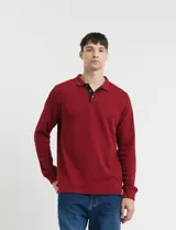 Remera de manga larga con cuello polo, confeccionada en tejido de punto canalé francés. Presenta abotonadura frontal con botones de madera y detalles a contratono en la cartera y el interior del cuello.