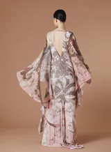 Vestido largo de seda con estampado barroco en tonos rosados y marrones, de corte al cuerpo con escote en V y mangas tipo capa amplias y fluidas.