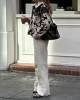 Campera con estampado de vaca en tonos marrón y blanco, de corte recto, con cuello camisero, cierre con botones a presión, bolsillos de parche en el pecho y bolsillos laterales.