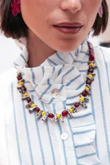 Collar corto compuesto por una secuencia de bastones de piedra natural con patrón de puntos, cuentas de vidrio amarillas y cristales checos en color bordó. Incluye cadena de extensión para regular el largo.