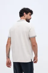 Chomba de piqué en color negro, de manga corta, con cuello y puños tejidos con líneas a contraste. Presenta cierre frontal parcial con botones y pequeño logo bordado en el pecho.