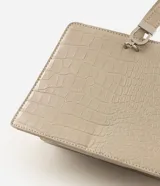Cartera de mano Satinato de diseño rígido y estructurado, confeccionada en PU con textura croco de color beige. Cuenta con una manija superior corta, cierre con botón magnético y herrajes plateados.