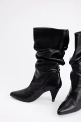 Bota de caña media en cuero negro con diseño slouchy, punta fina y taco cónico de altura media.